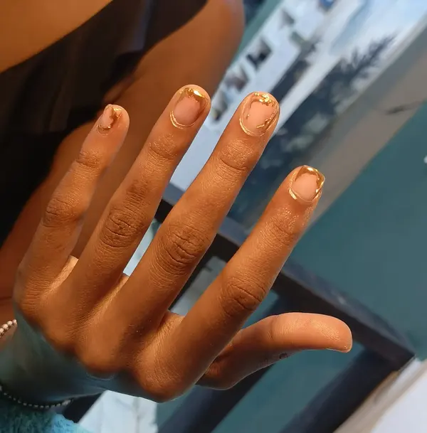 Short nude nails edged with organic gold outlines, supplied by NBD