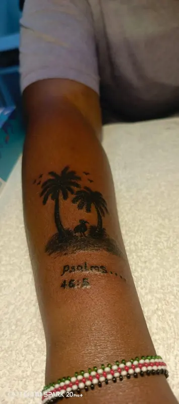 Palm trees and birds tattoo with lettering on a forearm, supplied by NBD